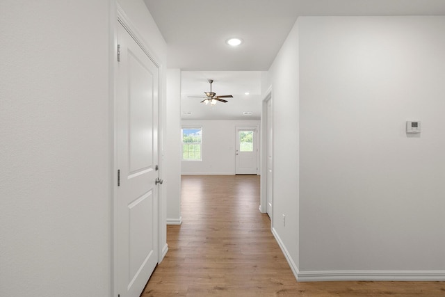 hallway with light wood finished floors, baseboards, and recessed lighting