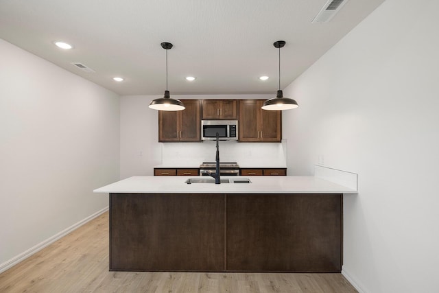 kitchen featuring stainless steel appliances, baseboards, light wood-type flooring, and visible vents