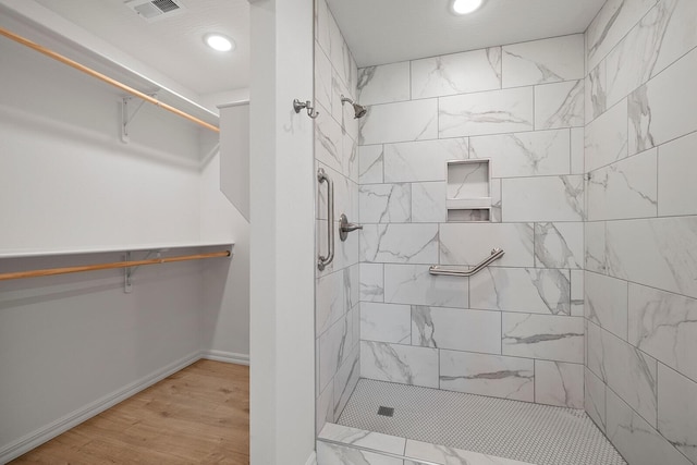 full bath featuring tiled shower, visible vents, and recessed lighting