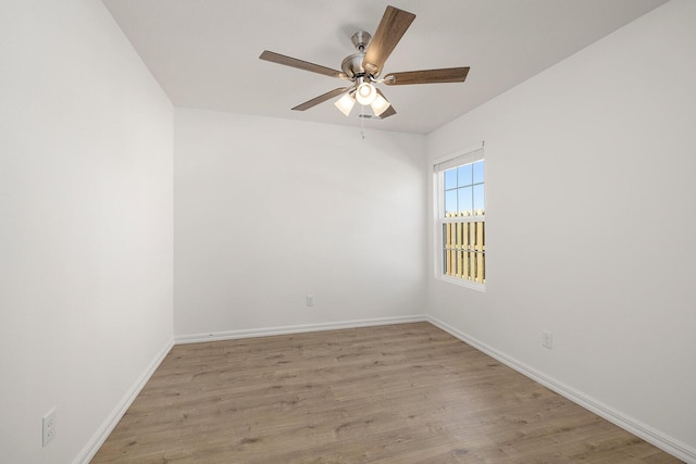 spare room with baseboards, light wood-type flooring, and a ceiling fan