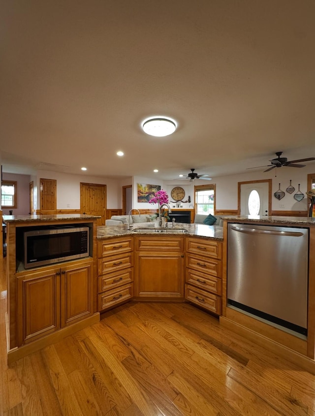 kitchen with a sink, light wood-style flooring, a ceiling fan, and appliances with stainless steel finishes