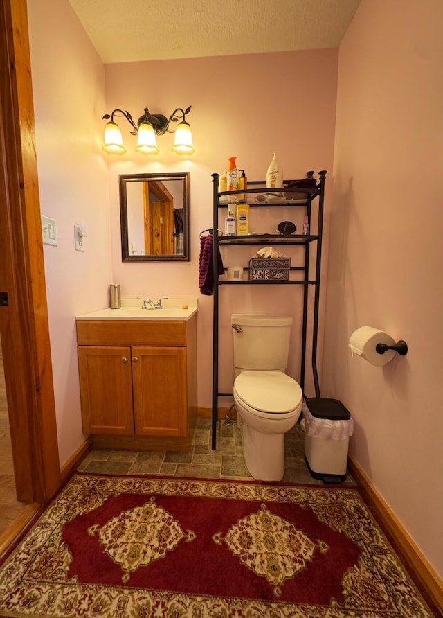 bathroom featuring toilet, baseboards, and vanity