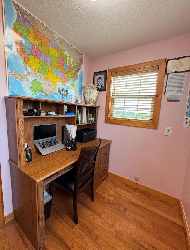 office with a textured ceiling, baseboards, and light wood-type flooring