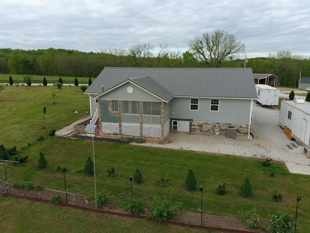 view of front of property with central air condition unit, a sunroom, metal roof, and a front lawn