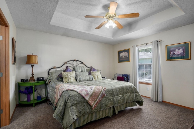 bedroom with a ceiling fan, a tray ceiling, carpet, a textured ceiling, and baseboards
