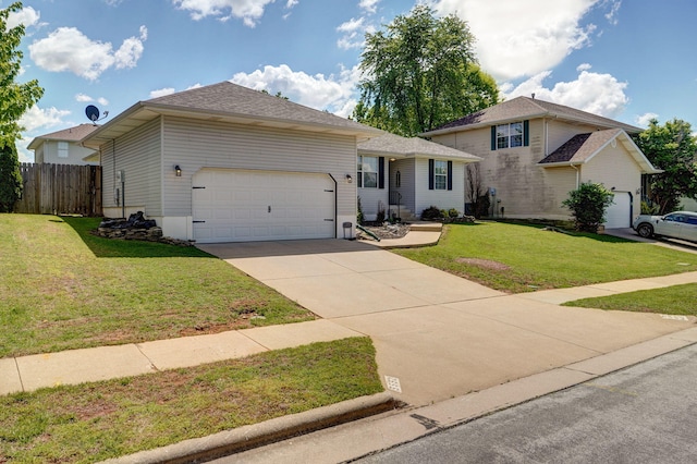 view of front of home featuring a front yard, driveway, fence, and a garage