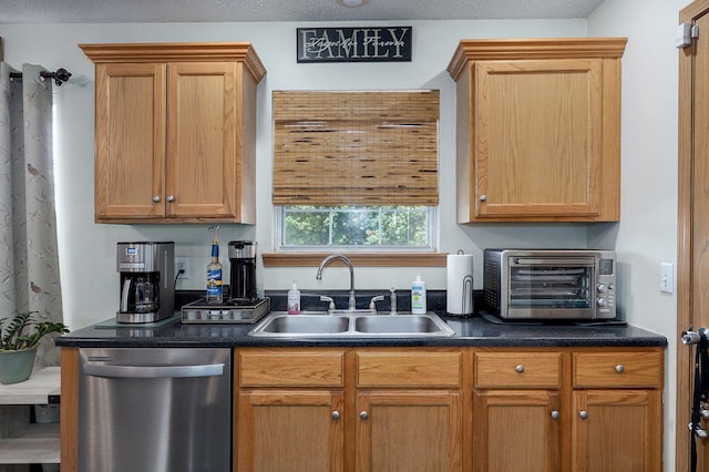 kitchen with dark countertops, a sink, a toaster, and stainless steel dishwasher