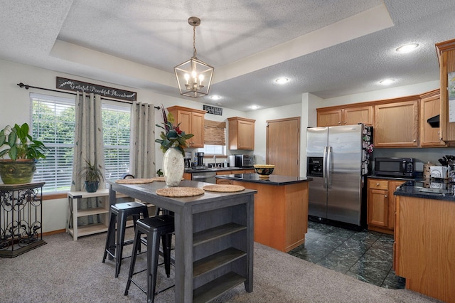 kitchen featuring a textured ceiling, a center island, an inviting chandelier, dark countertops, and appliances with stainless steel finishes