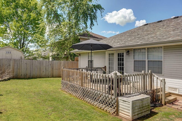 rear view of house with a yard, a wooden deck, a shingled roof, and a fenced backyard