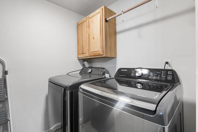 washroom featuring cabinet space and washer and clothes dryer