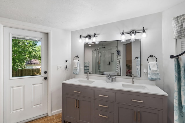 full bath with double vanity, wood finished floors, a shower stall, and a sink