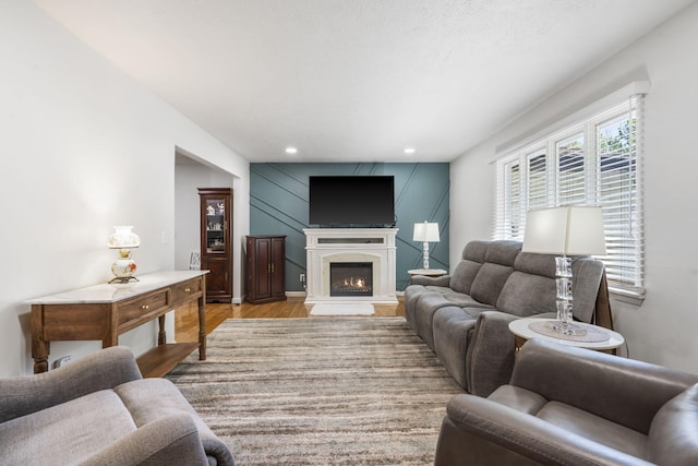 living room featuring a high end fireplace, light wood finished floors, a decorative wall, and recessed lighting
