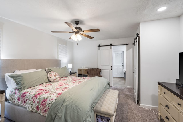 carpeted bedroom with baseboards, ceiling fan, and a barn door