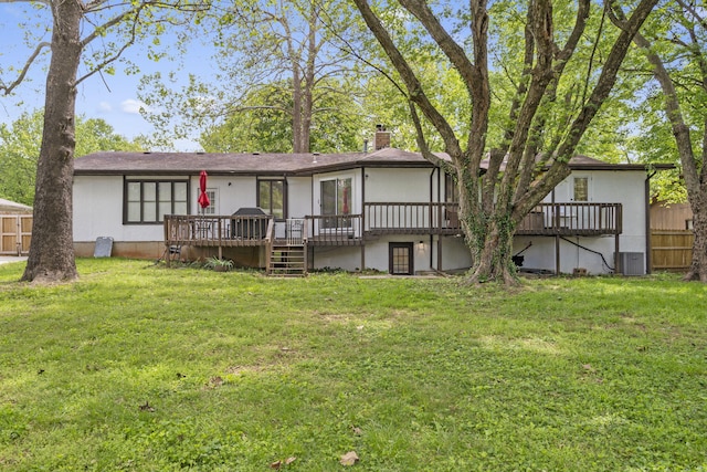 rear view of house featuring a chimney, a deck, a yard, and fence