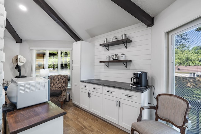 mudroom featuring a wealth of natural light, beam ceiling, wood walls, and wood finished floors
