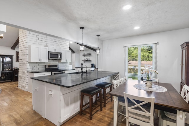 kitchen featuring a textured ceiling, stainless steel appliances, a sink, and white cabinetry