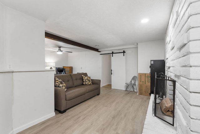 living area with baseboards, beamed ceiling, light wood finished floors, and a barn door