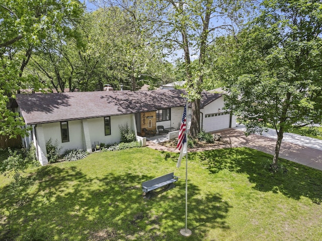 ranch-style home with an attached garage, stucco siding, concrete driveway, a shingled roof, and a front lawn