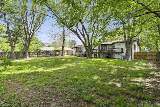 view of yard with a fenced backyard, a wooden deck, and stairway