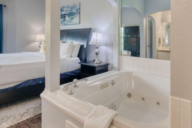 813 Holiday Rdg Unit H-11, Branson, MO 65616 - bathroom featuring wood finished floors, a whirlpool tub, ensuite bathroom, a textured wall, and vanity