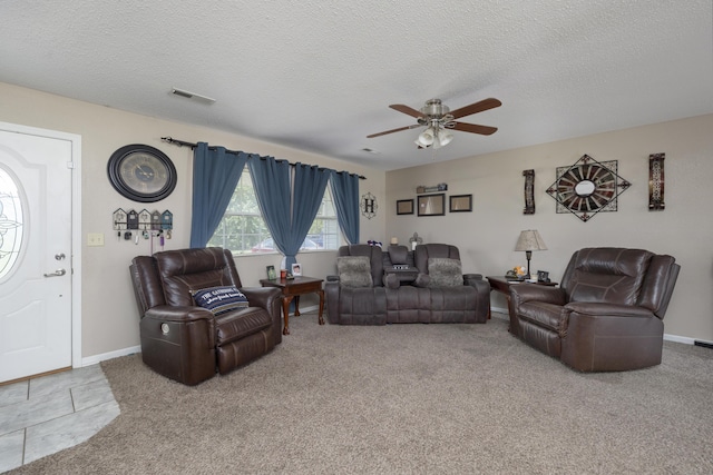 living area featuring a ceiling fan, a textured ceiling, baseboards, carpet flooring, and visible vents