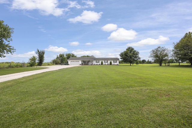 view of front facade with dirt driveway, a front yard, and a garage