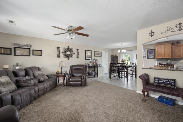 living room with light carpet, a textured ceiling, ceiling fan with notable chandelier, and visible vents