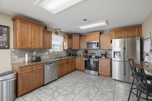 kitchen featuring appliances with stainless steel finishes, visible vents, and brown cabinets
