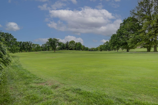 view of home's community featuring golf course view, a yard, and view of wooded area