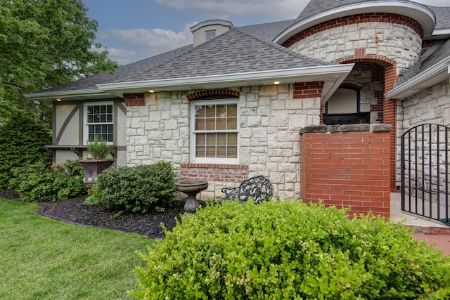 view of home's exterior featuring a gate, roof with shingles, a chimney, and stone siding