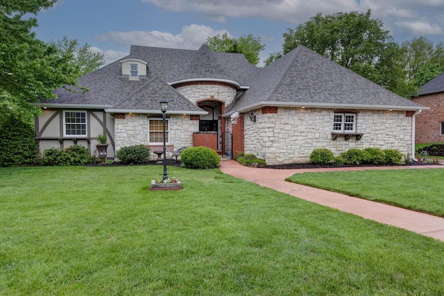 view of front of house featuring a shingled roof, a front lawn, and stone siding