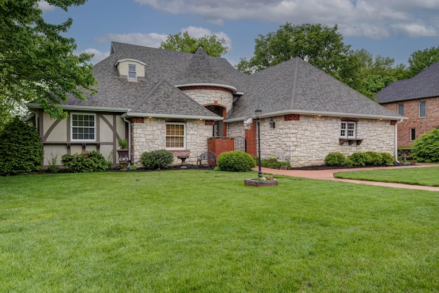 view of front of property featuring stone siding, roof with shingles, and a front yard