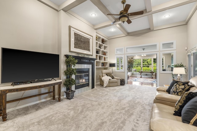 living area with coffered ceiling, a tile fireplace, a ceiling fan, carpet floors, and beam ceiling