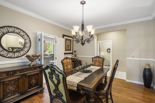 dining area featuring a chandelier, wood finished floors, ornamental molding, and baseboards