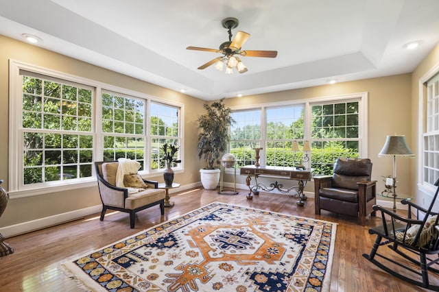 living area featuring a raised ceiling, hardwood / wood-style flooring, healthy amount of natural light, a ceiling fan, and recessed lighting