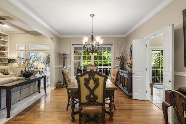 dining space featuring a chandelier, wood finished floors, crown molding, and a ceiling fan