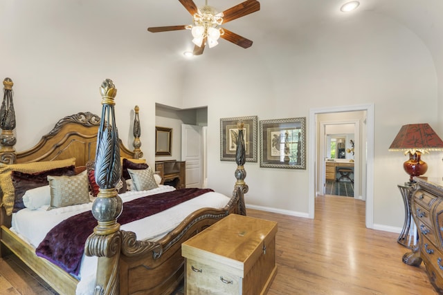bedroom featuring baseboards, wood finished floors, high vaulted ceiling, and a ceiling fan