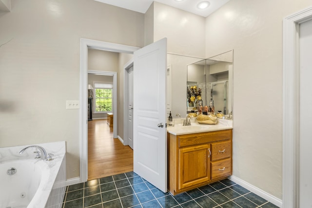 bathroom featuring a tub with jets, vanity, tile patterned floors, a shower stall, and baseboards
