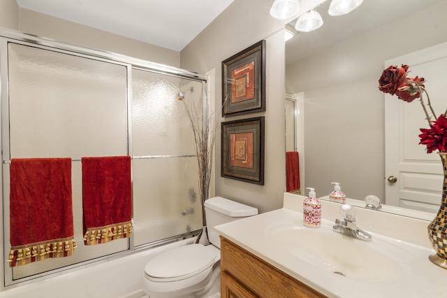 full bathroom featuring vanity, combined bath / shower with glass door, and toilet