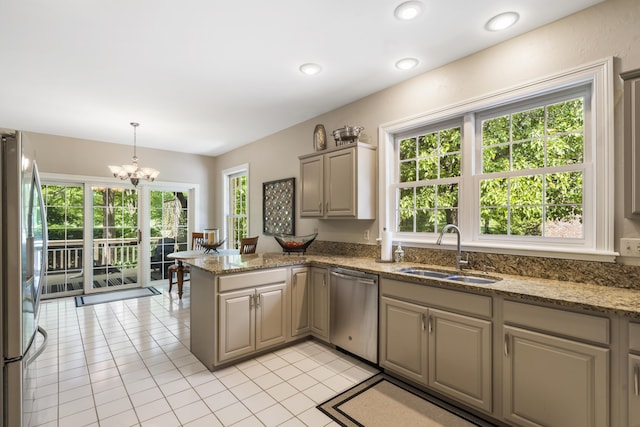 kitchen featuring a sink, stainless steel appliances, light tile patterned flooring, a peninsula, and a chandelier