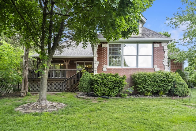 back of house with brick siding, a shingled roof, a lawn, and a deck