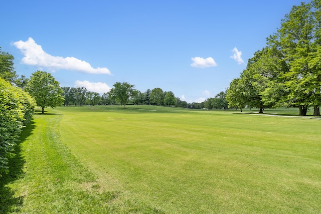 view of home's community featuring golf course view, a lawn, and view of scattered trees