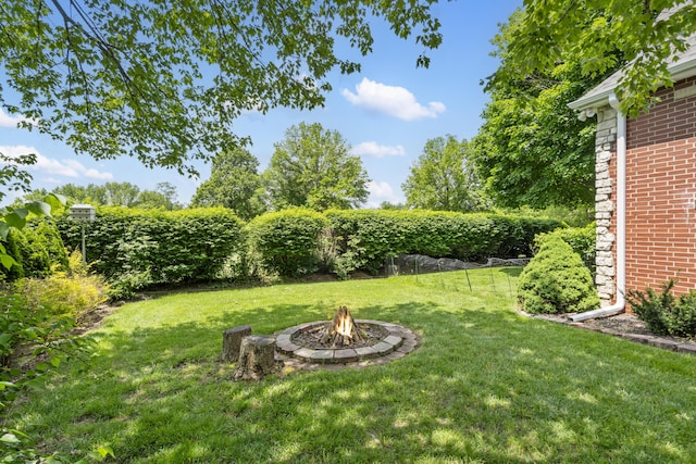view of green lawn with an outdoor fire pit