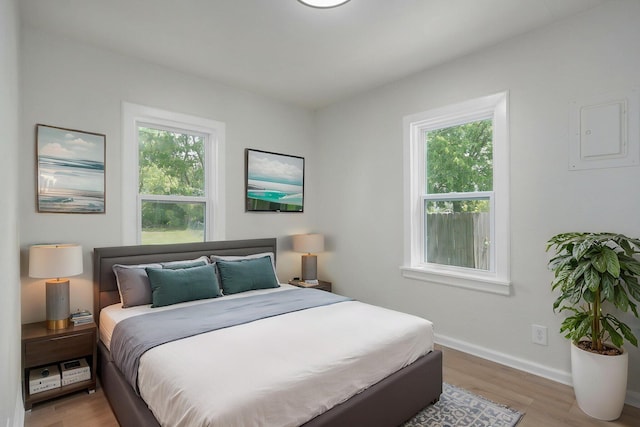 bedroom with light wood-style floors, baseboards, and multiple windows