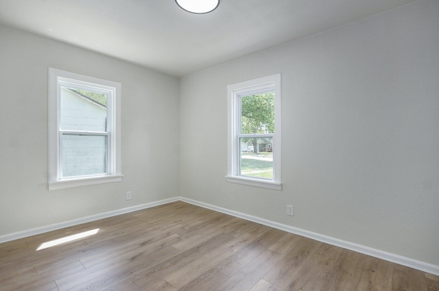 unfurnished room with baseboards and light wood-style flooring