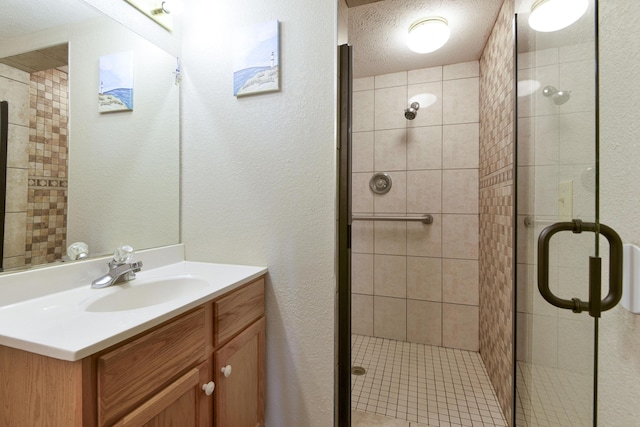 full bathroom with a textured ceiling, vanity, a shower stall, and a textured wall
