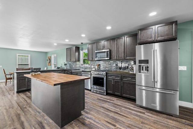 kitchen featuring appliances with stainless steel finishes, wooden counters, a peninsula, dark wood-style floors, and decorative backsplash