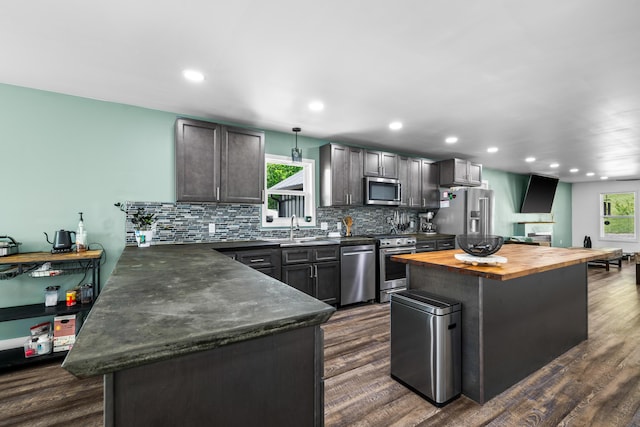 kitchen featuring stainless steel appliances, wood counters, dark wood-type flooring, and recessed lighting