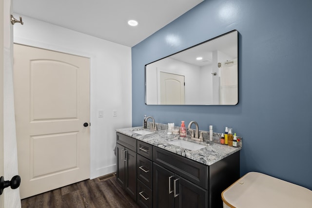 bathroom with wood finished floors, double vanity, baseboards, and recessed lighting