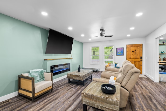 living area with ceiling fan, recessed lighting, dark wood-style flooring, a glass covered fireplace, and baseboards